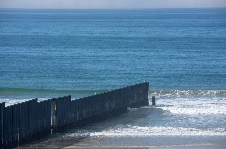 Shows a border wall going out into the Pacific Ocean